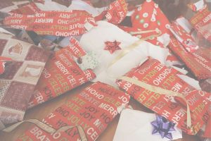 Torn holiday wrapping paper and gift packaging scattered on the floor, showing the clutter and overwhelm that often follow Christmas celebrations.