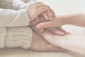Hands of parents and children resting together symbolizing emotional safety, connection, and generational healing in conscious parenting