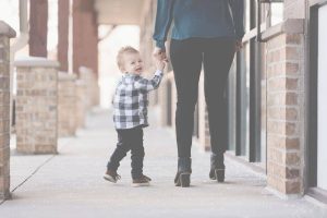 Toddler holding mother’s hand while looking upset, showing emotional connection and co-regulation in conscious parenting