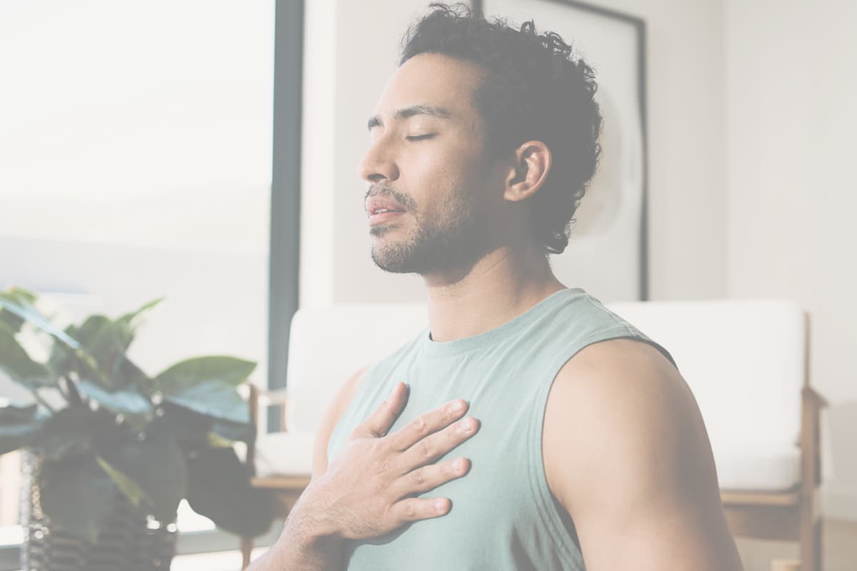 Person with eyes closed and hand on heart practicing self-reflection and emotional healing in a calm indoor space.
