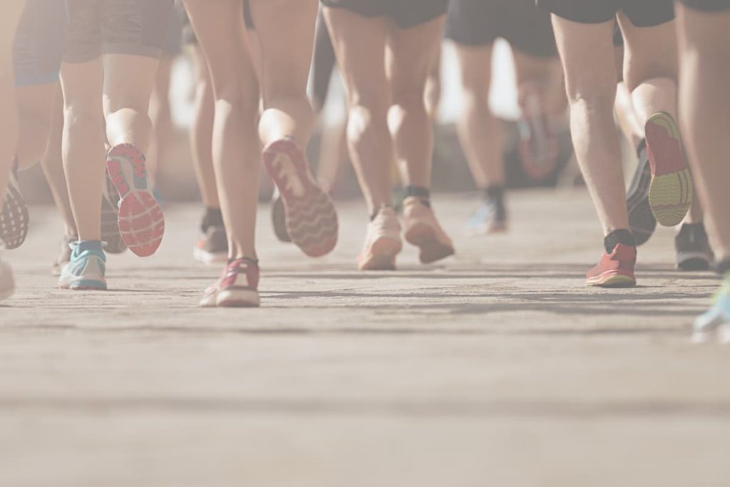 Close-up of runners' legs and colorful sneakers pushing forward during a race, symbolizing perseverance and pushing through challenges