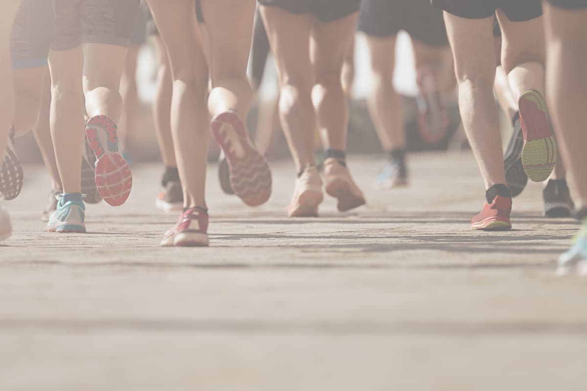 Close-up of runners' legs and colorful sneakers pushing forward during a race, symbolizing perseverance and pushing through challenges